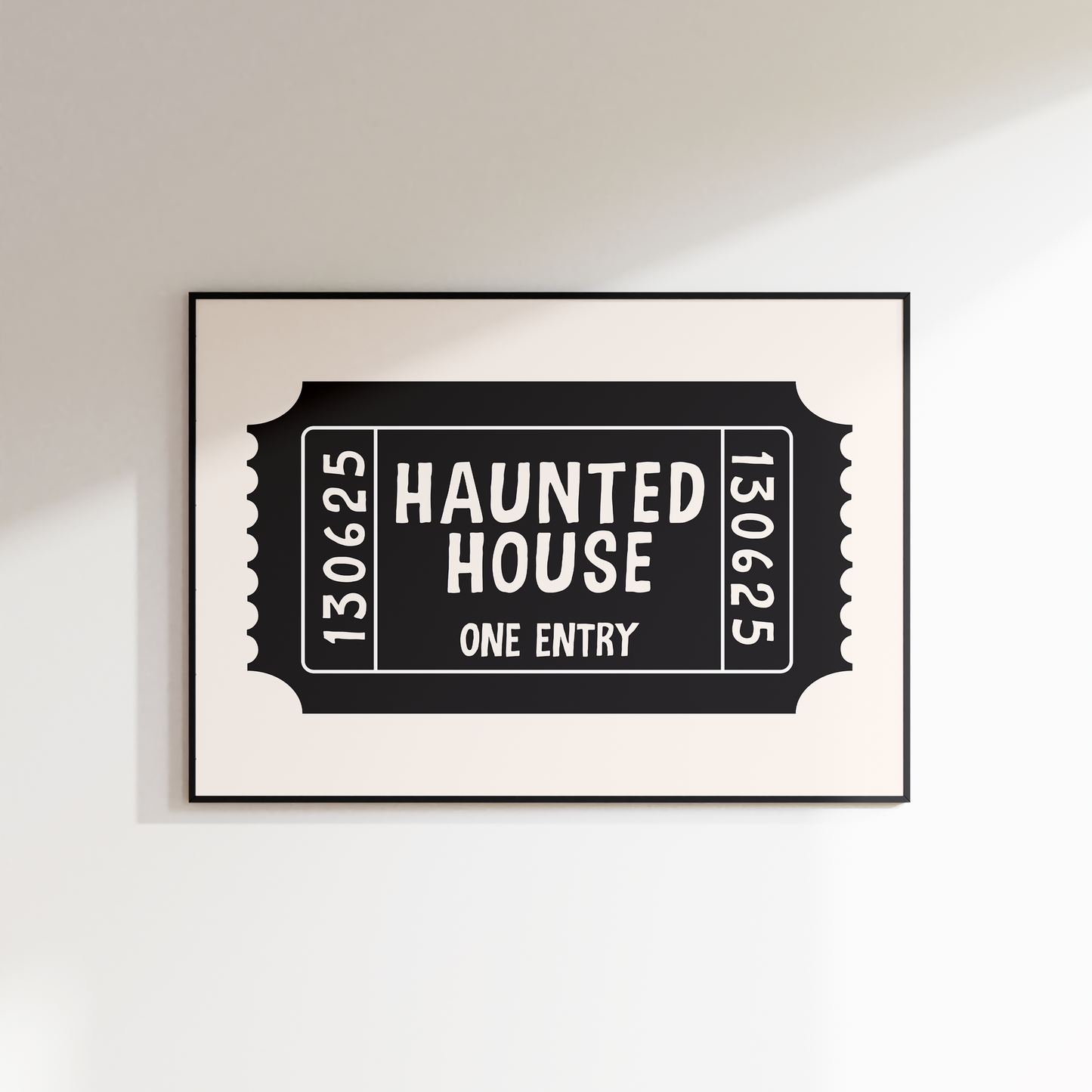Framed artwork of a 'Haunted House' ticket design on a white wall.