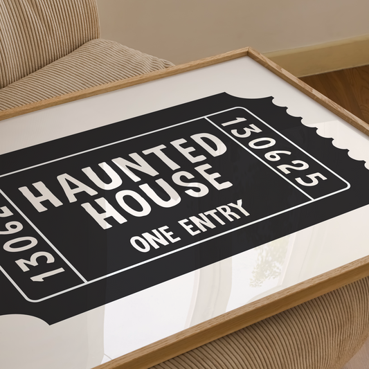 Framed 'Haunted House' ticket design on a white surface with a wooden frame.
