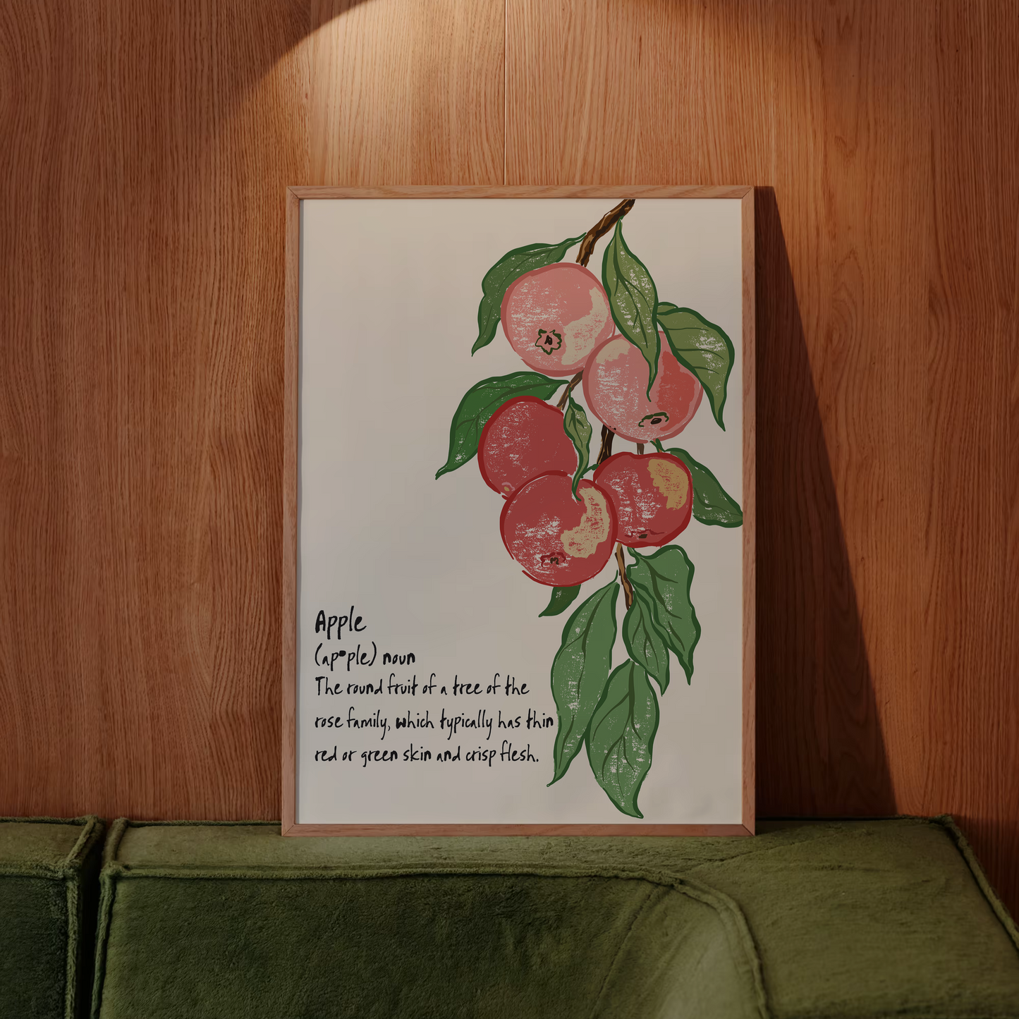 Framed artwork of apples on a wooden wall above a green sofa
