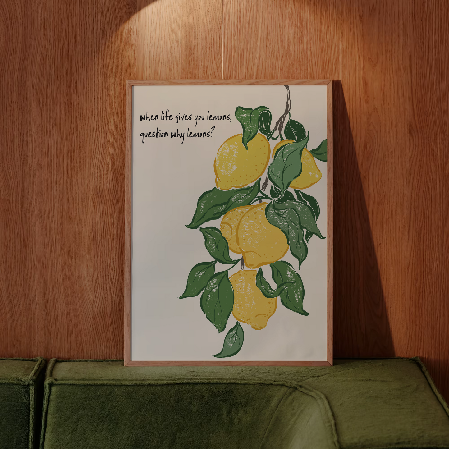 Framed artwork with lemons and text on a wooden wall above a green sofa.