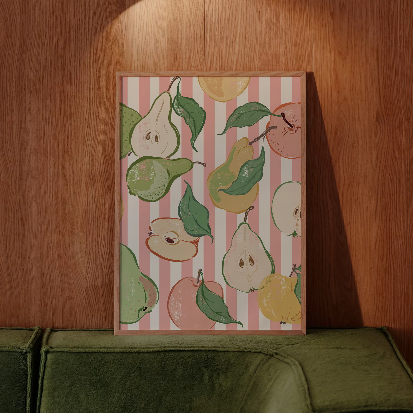 Framed artwork with pear illustrations on a pink striped background, leaning against a wooden wall.