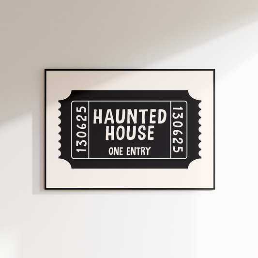 Framed artwork of a 'Haunted House' ticket design on a white wall.