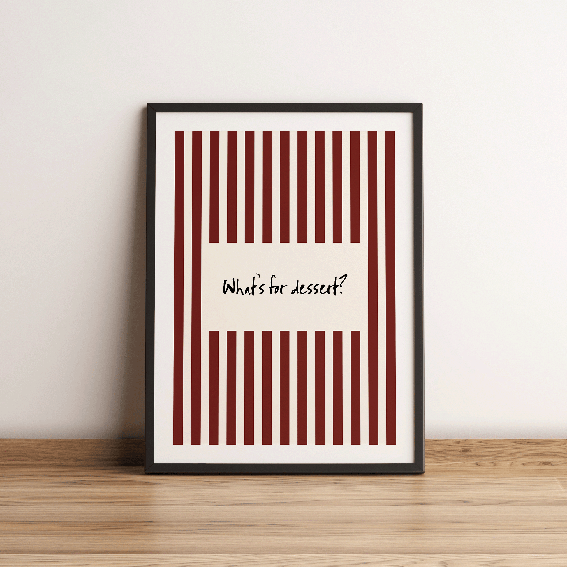 Framed poster with red and white striped design and text 'What's for dessert?' on a wooden surface.