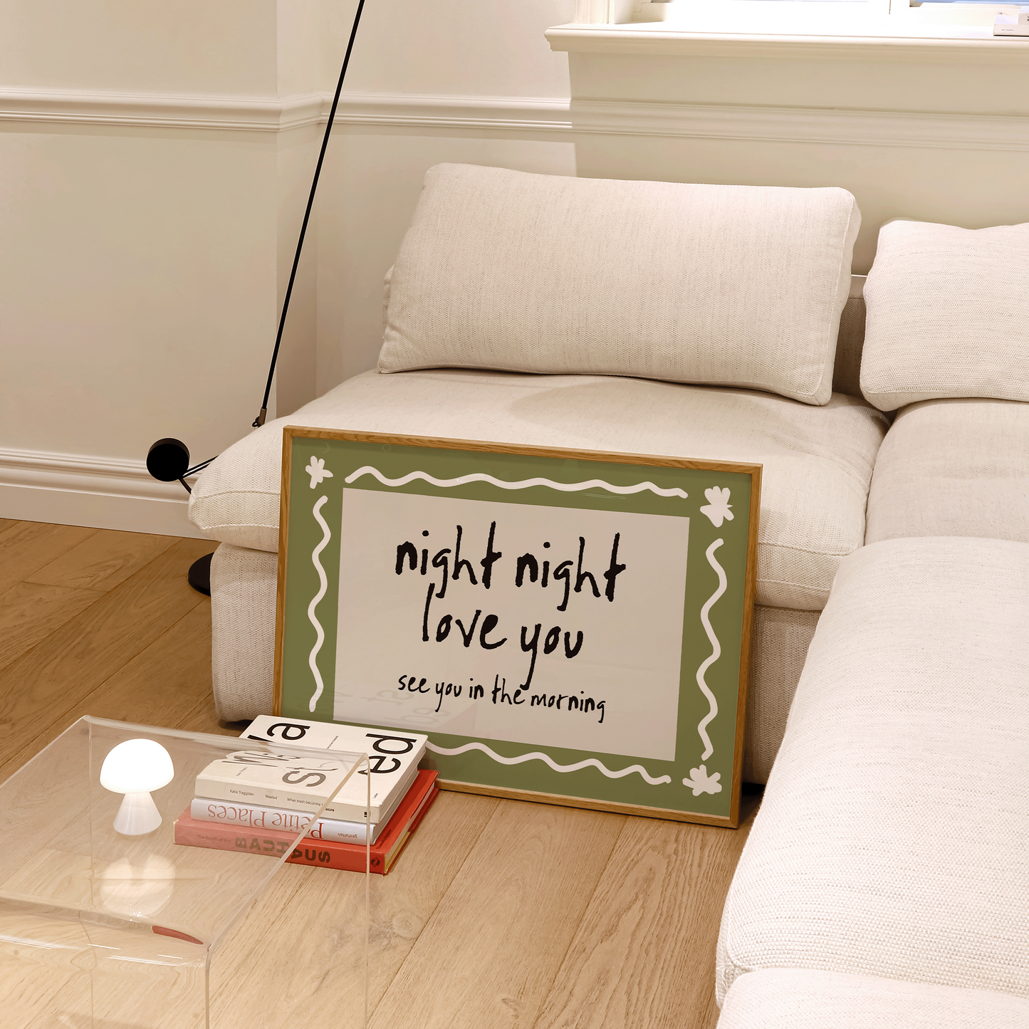 Living room with a white couch, lamp, and decorative sign on a glass table.