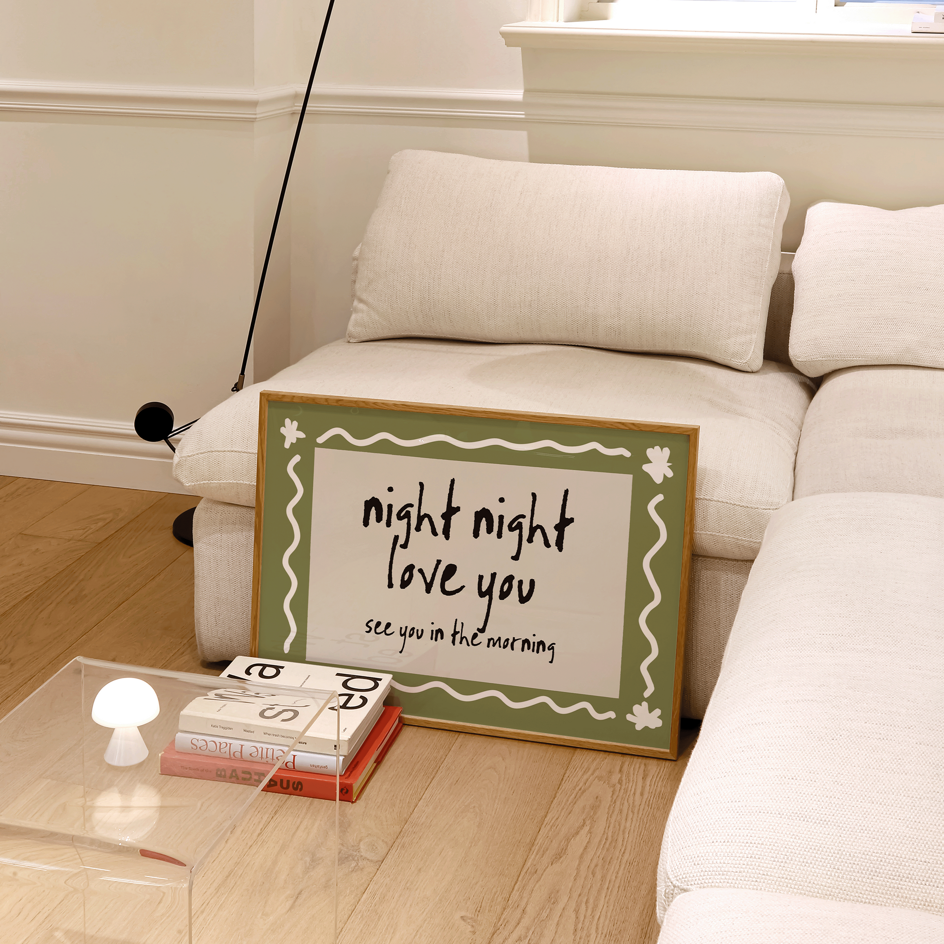 Living room with a white couch, lamp, and decorative sign on a glass table.