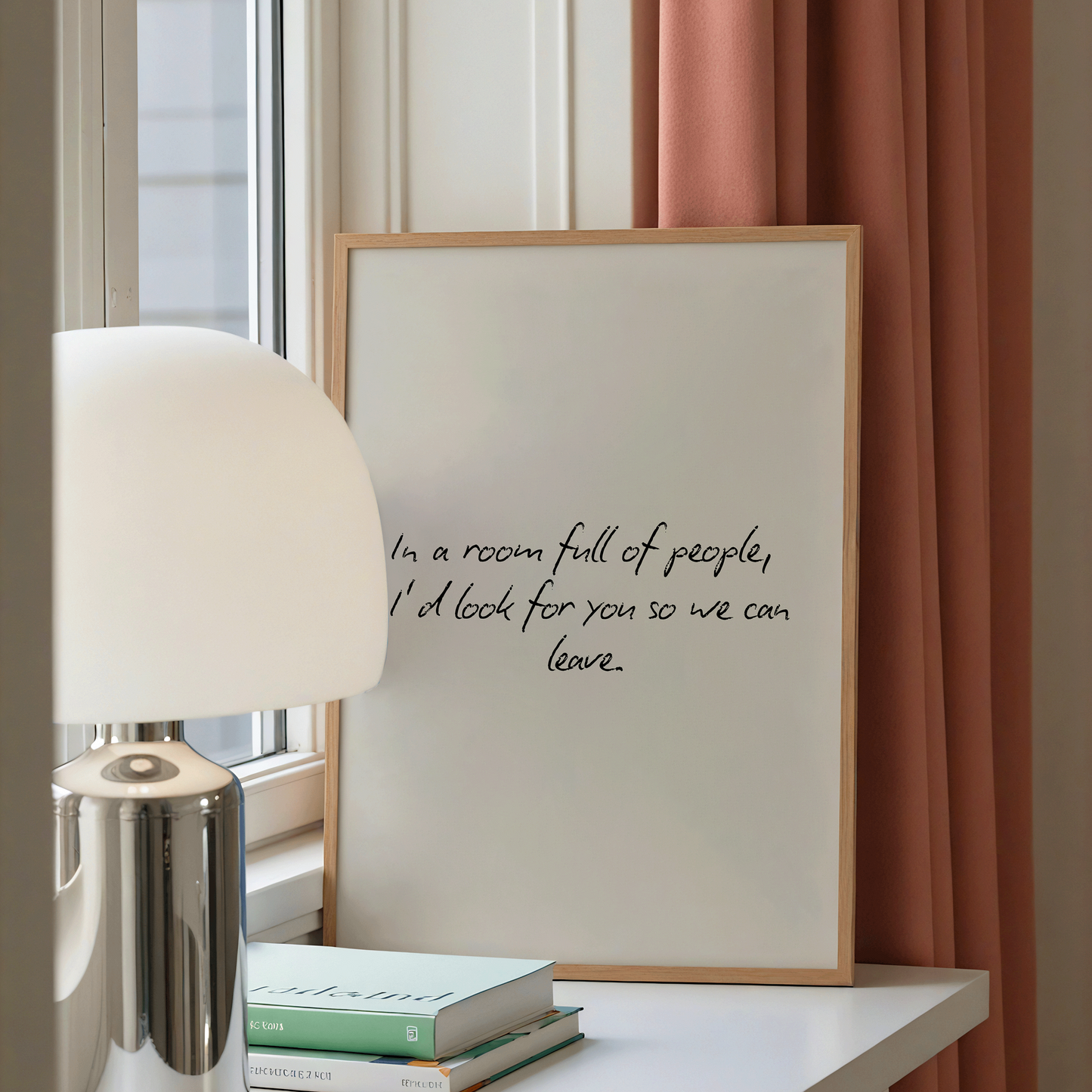 Framed quote on a table with a lamp and books in a room with pink curtains.