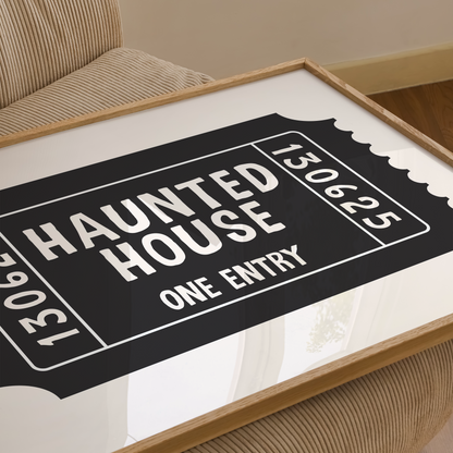 Framed 'Haunted House' ticket design on a white surface with a wooden frame.