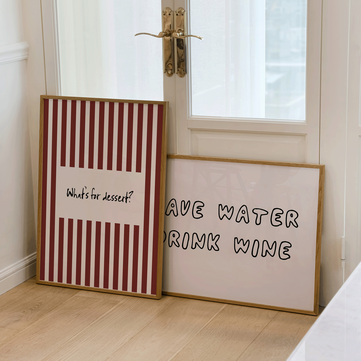 Two framed prints on a wooden floor with a glass door in the background.

One wall art says what's for dessert, the other piece of wall art says "save water, drink wine"