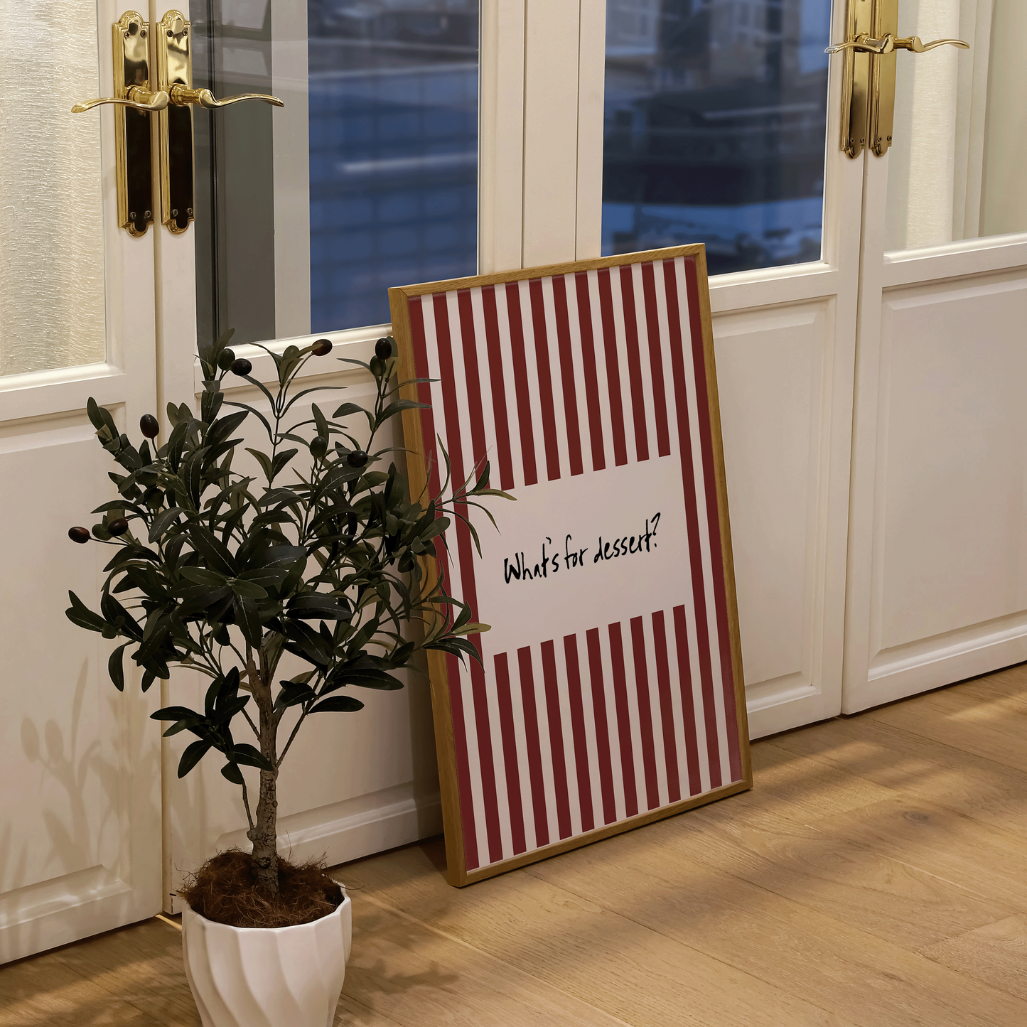 Decorative sign with striped pattern and text next to a potted plant in a room with large windows.