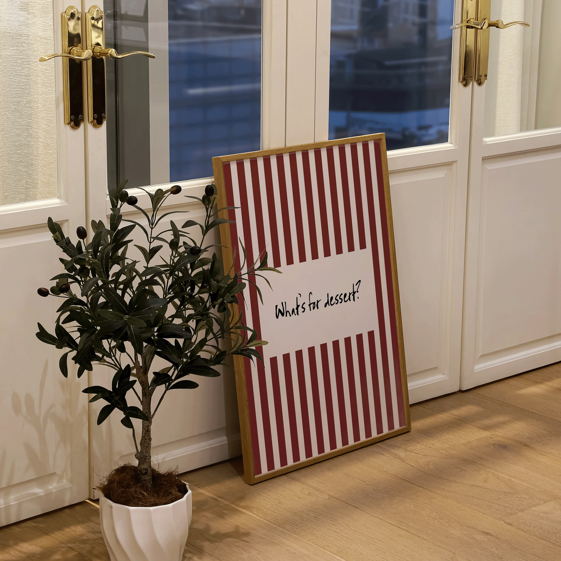 Decorative sign with striped pattern and text next to a potted plant in a room with large windows.