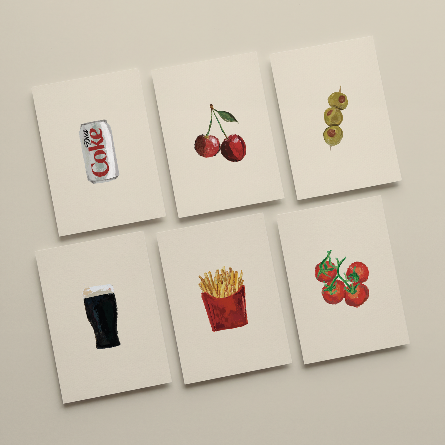 Six square cream art prints arranged in a 2x3 grid on a light beige wall. Each print features a different watercolor-style food or drink illustration: a Coke can, two red cherries, three green olives, a dark beer glass, a red french fries container with yellow fries, and red tomatoes with green stems.
