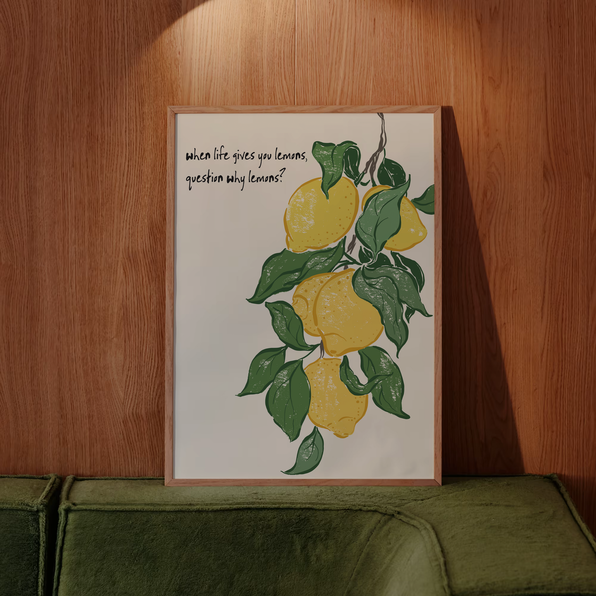 Framed artwork with lemons and text on a wooden wall above a green sofa.