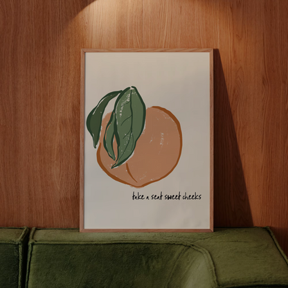Framed artwork of a peach with leaves on a wooden wall above a green sofa.