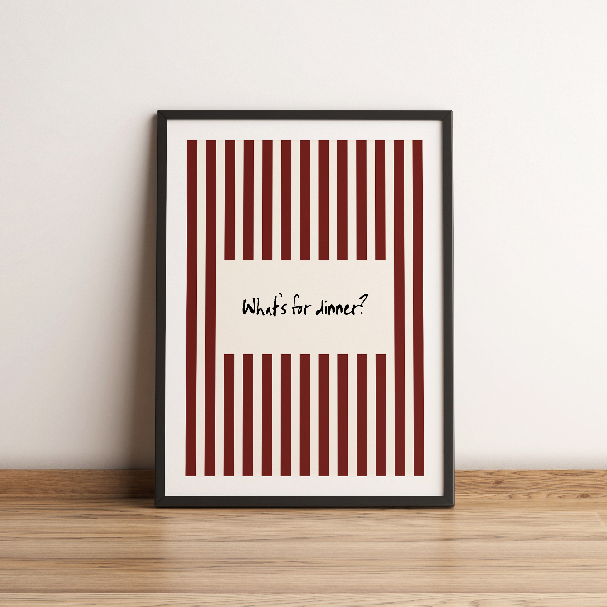 Framed poster with red and white striped design and text 'What's for dinner?' on a wooden surface.