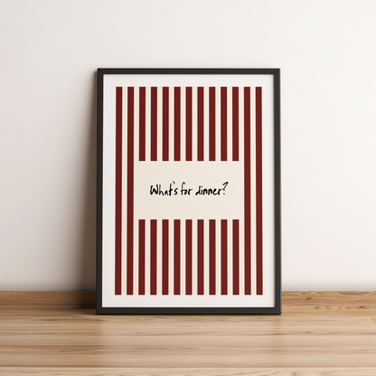 Framed poster with red and white striped design and text 'What's for dinner?' on a wooden surface.